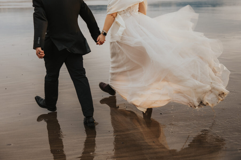 Bride and groom walking on windy beach