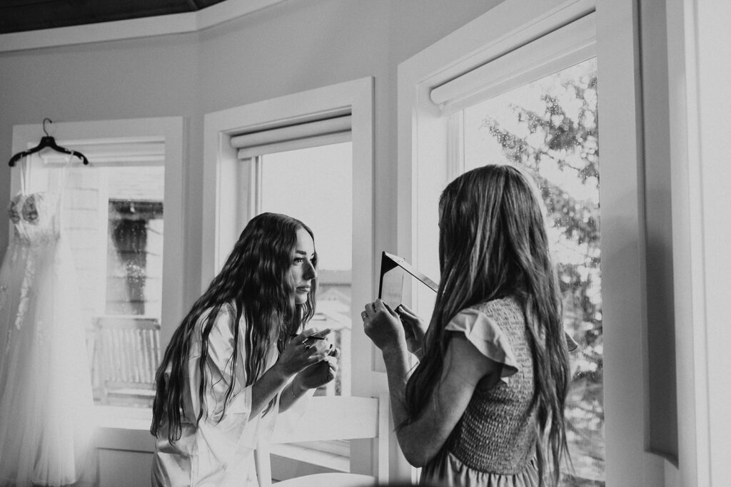 Younger sister helping bride get ready for wedding