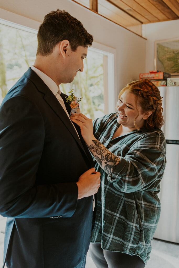 Bride helping groom with his boutonniere 