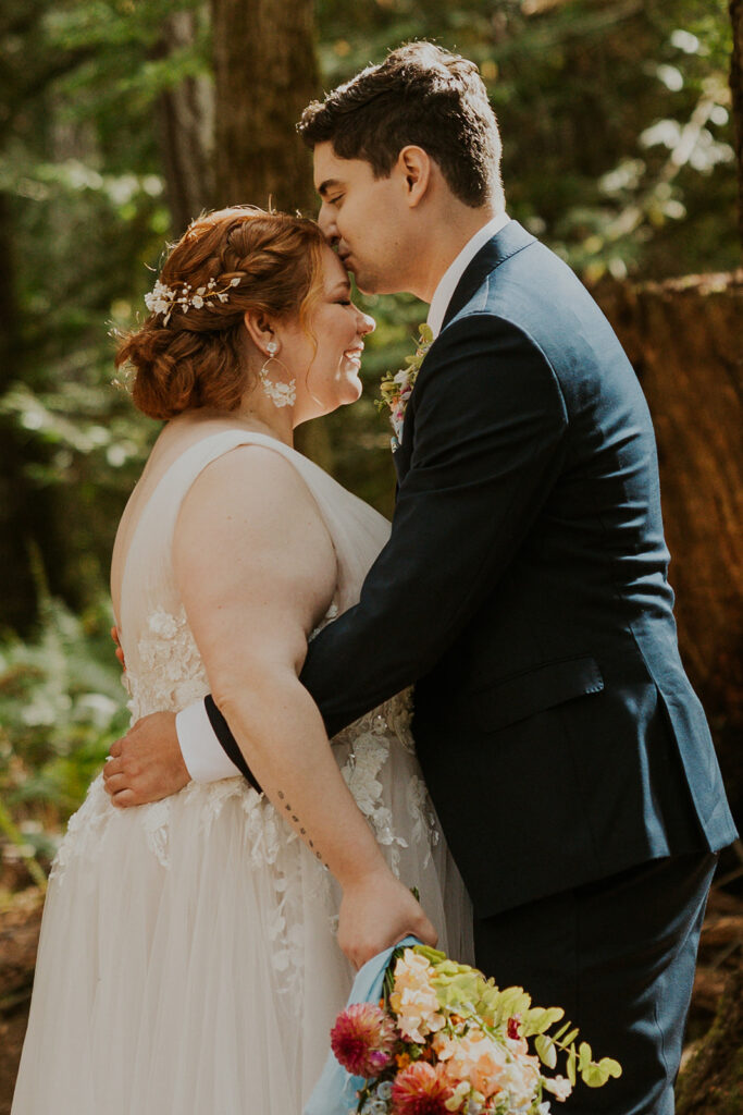 A couple in wedding attire pose in a forest in Olympic National Park