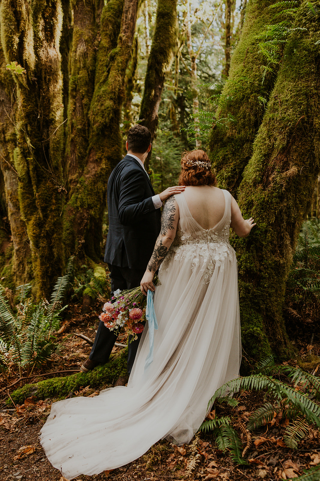 A couple in wedding attire pose in a forest in Olympic National Park