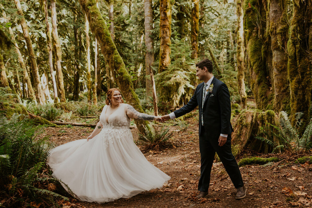 A couple in wedding attire pose in a forest in Olympic National Park