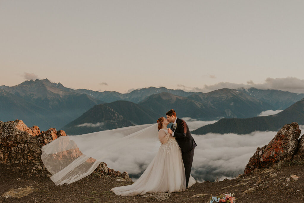 A couple in wedding attire with an Olympic National Park mountain range in the background