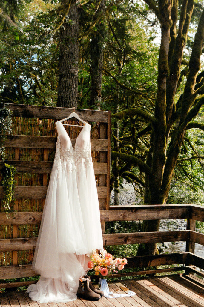 Wedding dress hanging up outside a vacation rental with a forest in the background on 35mm film