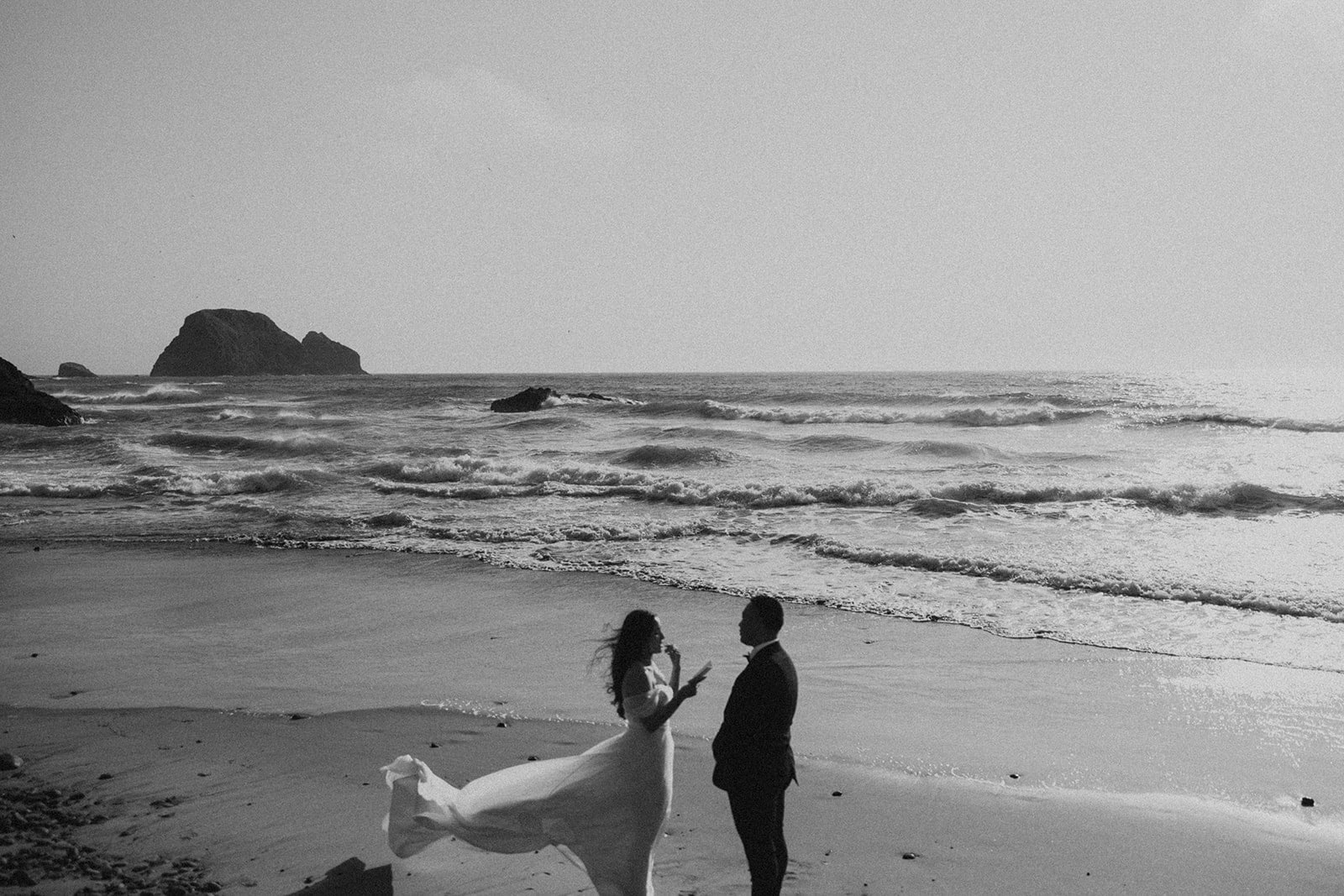 Black and white photo of a couple getting married on an Oregon Coast beach during their elopement