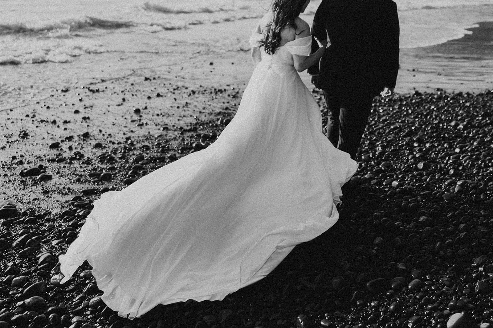 Bride's dress blowing in the wind while walking on an Oregon Coast beach