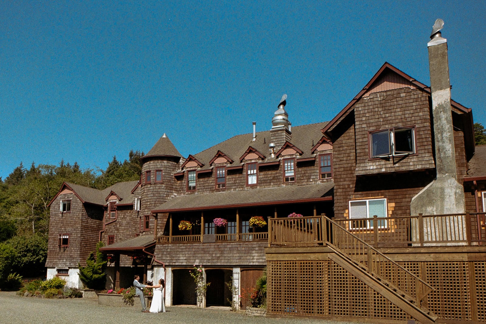 An eloping couple stands in front of Arch Cape Inn in Cannon Beach, OR on 35mm film