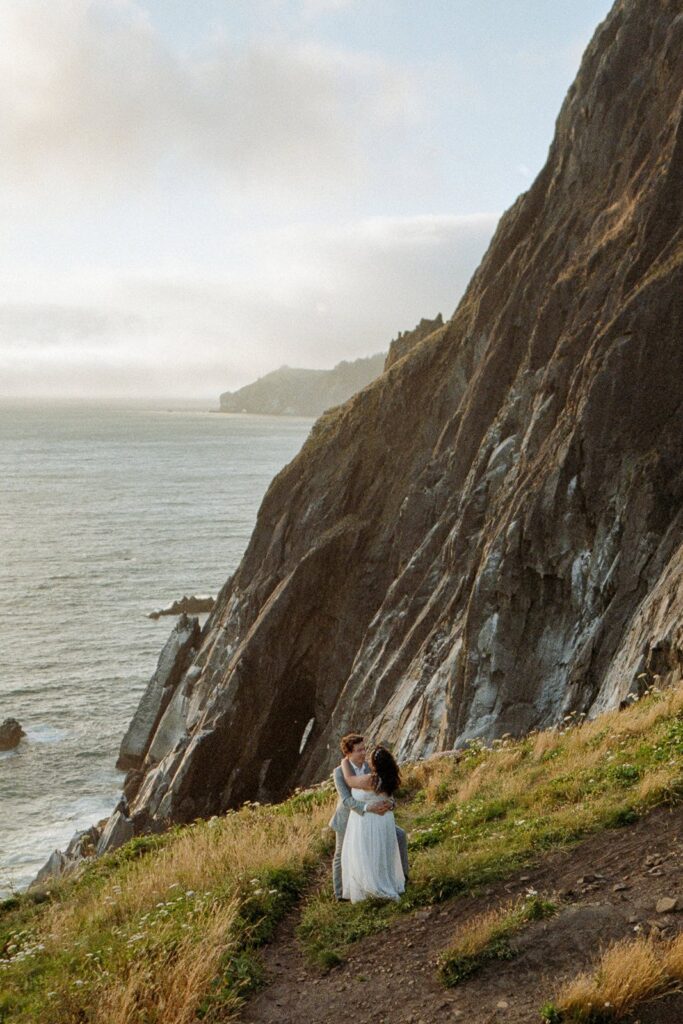 A couple standing on a cliff edge on the Oregon Coast during their elopement day on 35mm film