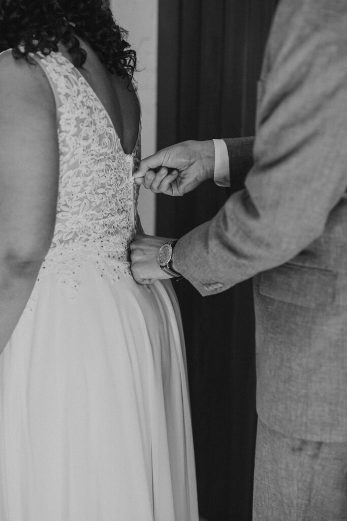 Groom zipping up bride's dress