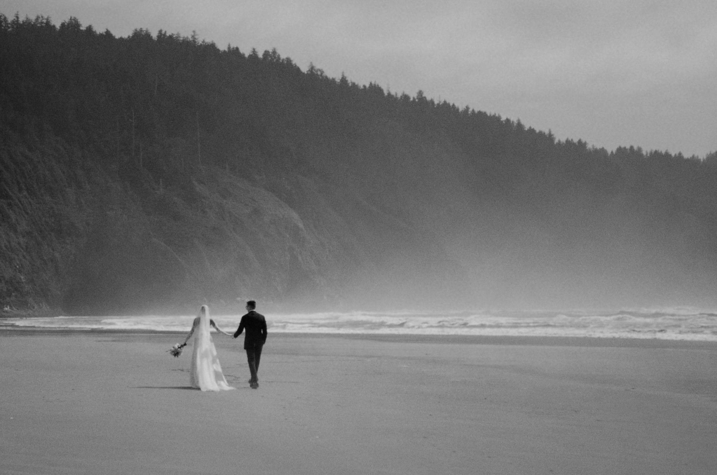 A couple walking on the beach during their elopement day, captured on film in black and white