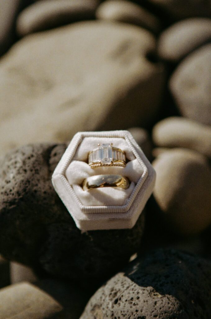 An emerald cut wedding ring and groom's band in a ring box on the beach on the Oregon Coast on 35mm film