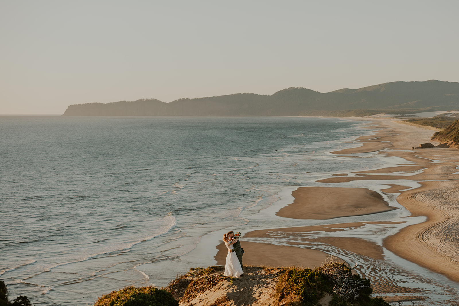 A couple on their elopement day standing on Cape Kiwanda dune in Pacific City, OR